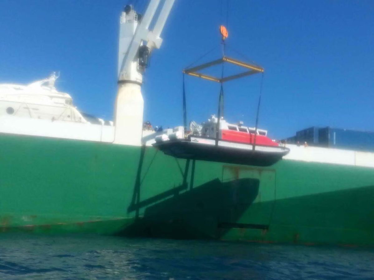 Yeşil gemi gövdesinin yanında gemi vincinden asılı tekne